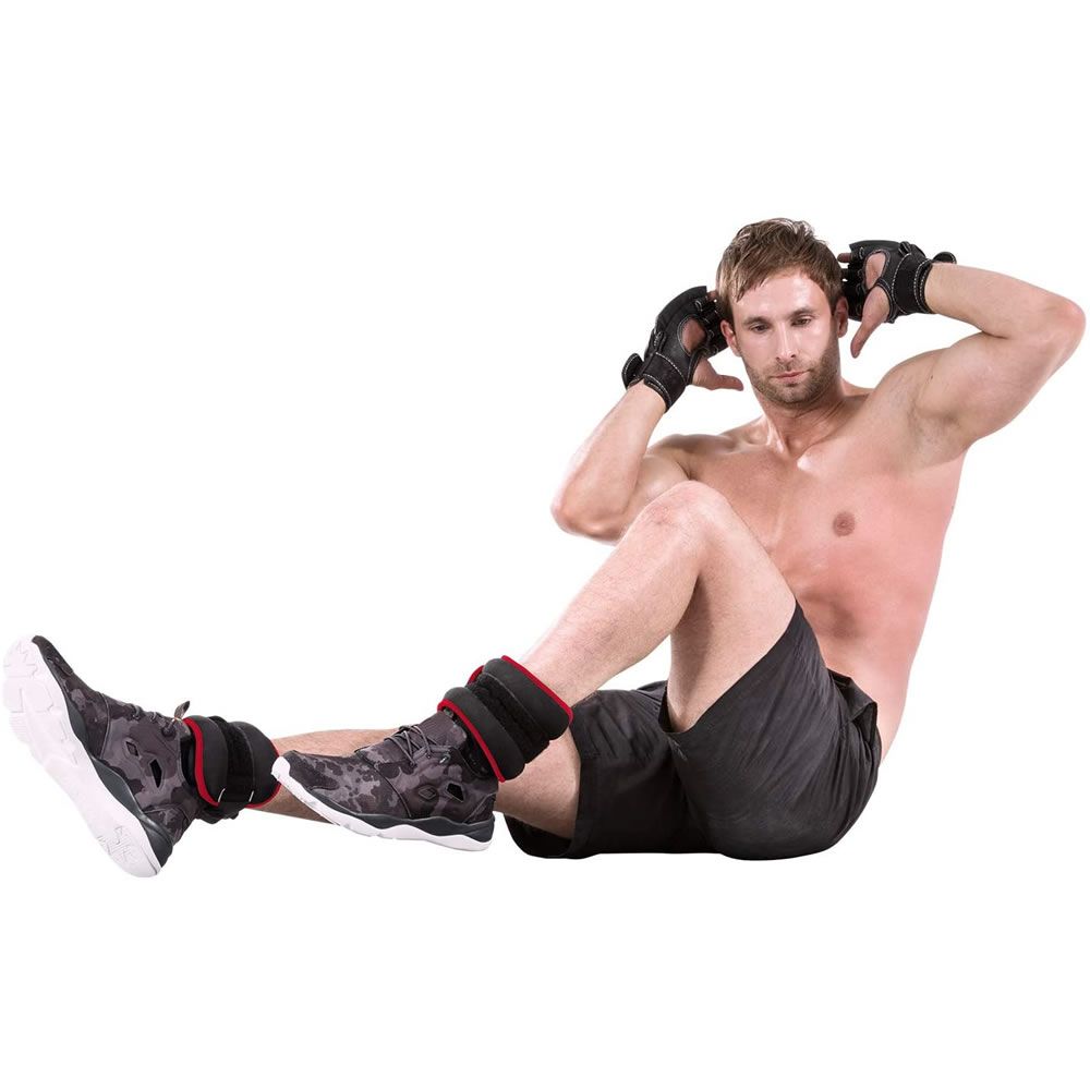 Mann macht Sit-ups mit schwarzen und roten Gewichtsmanschetten an den Knöcheln. Er trägt Handschuhe. Hintergrund weiß.