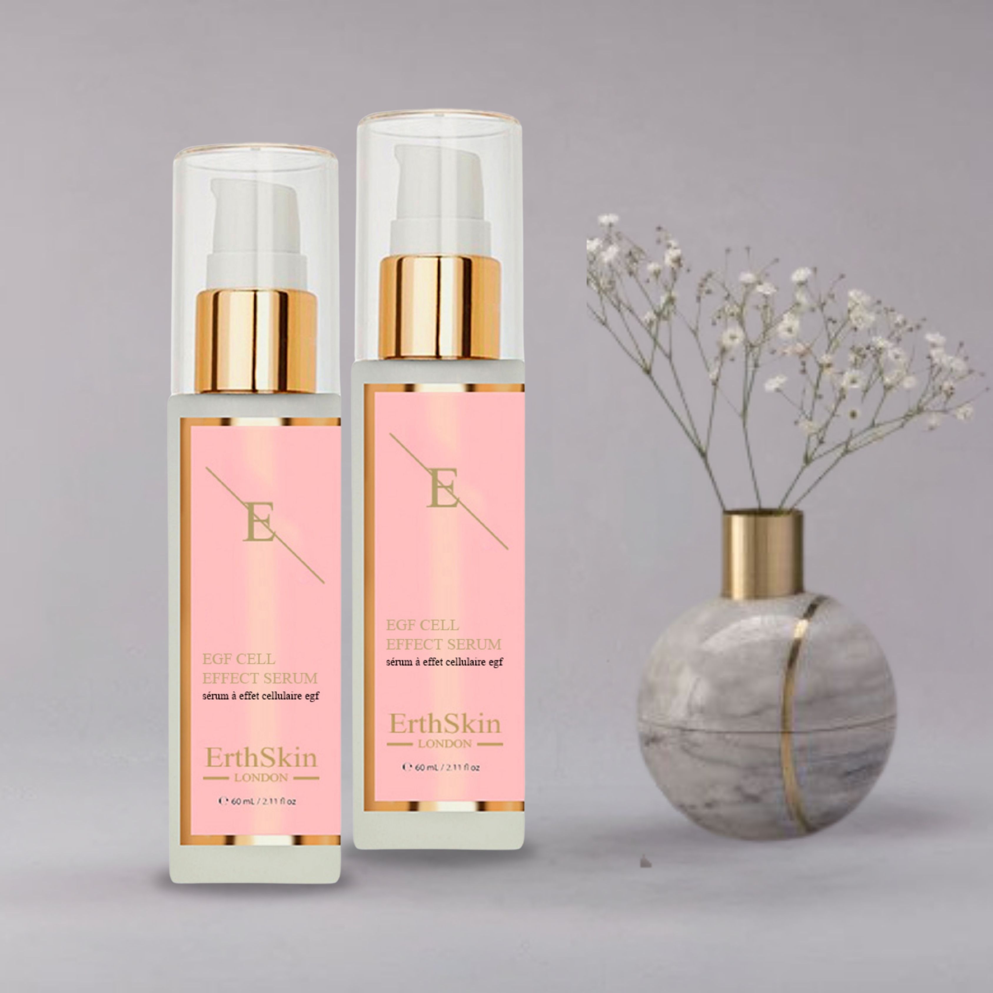 Twee ErthSkin London EGF ZELL EFFEKTSERUM flessen. Roze etiketten met tekst. Gouden pompkopjes en transparante doppen. Vaas met bloemen.