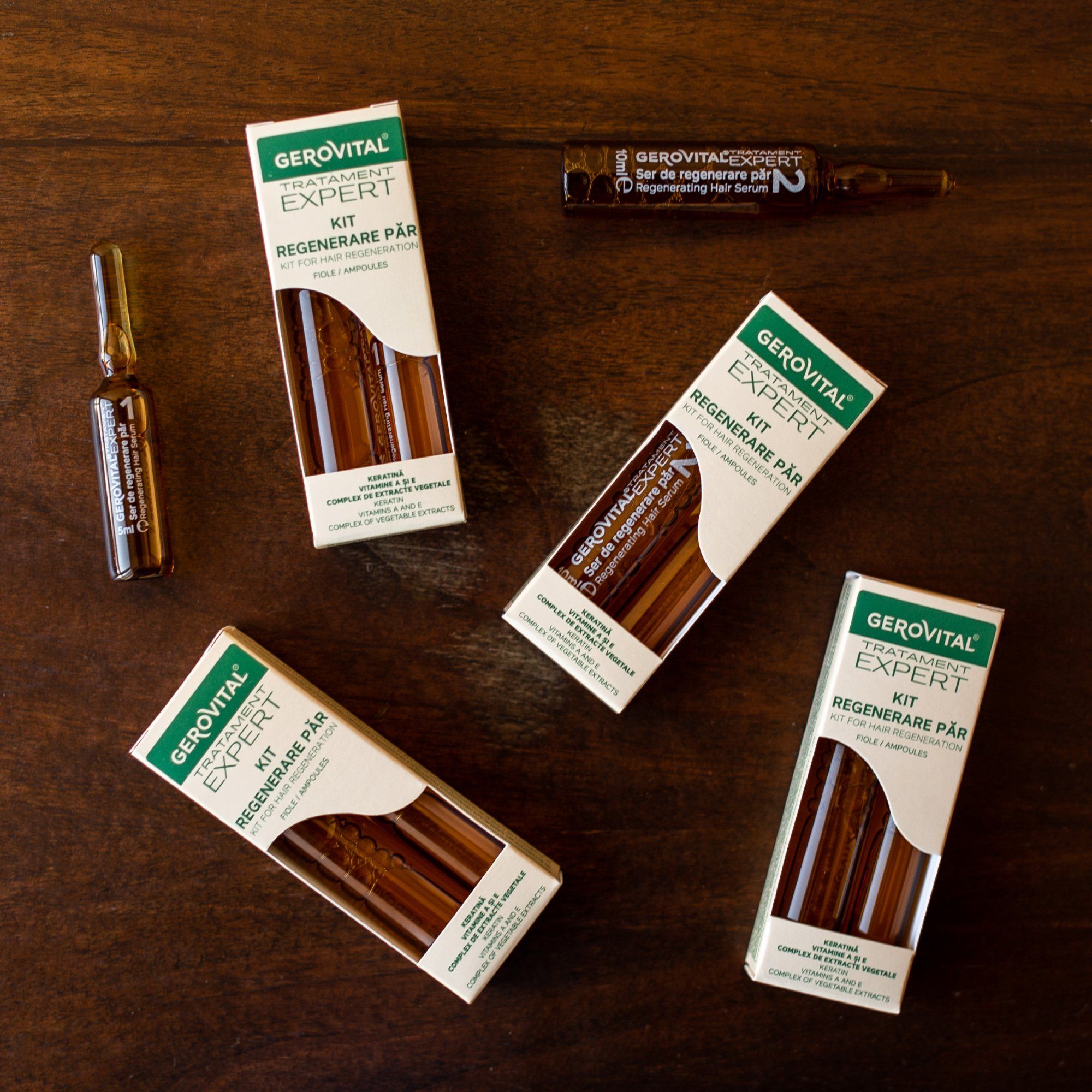 Mehrere Gerovital Expert Kits und eine Ampulle auf Holzuntergrund. Verpackungen mit grünen Akzenten und Produktnamen.