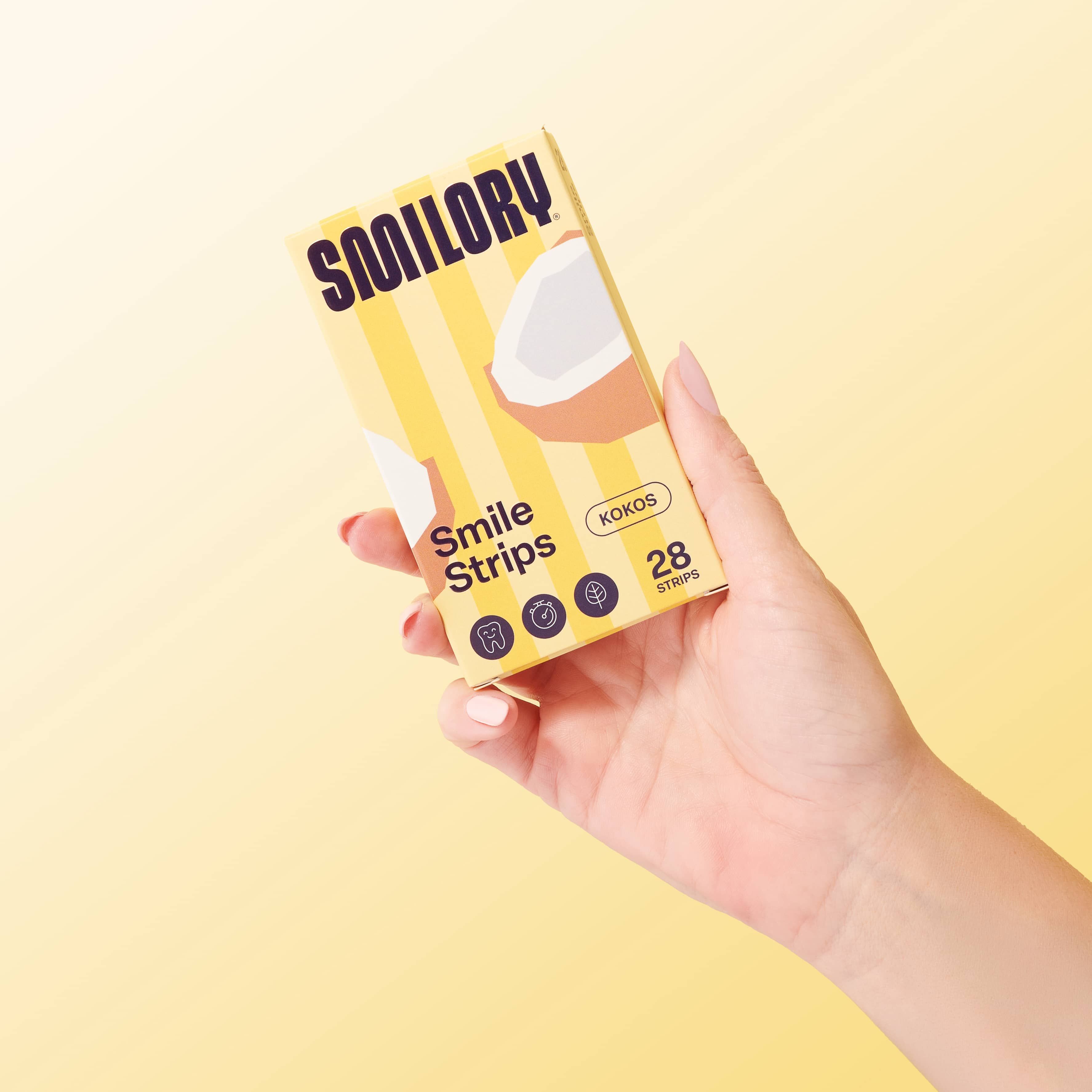 Hand hält Smilory Smile Strips Kokos-Verpackung. Gelb mit Kokosnuss-Illustration. 28 Streifen.