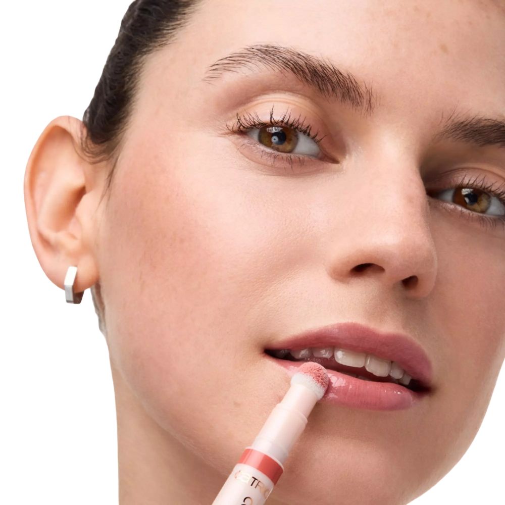 Frau trägt Lippenprodukt mit Applikator auf.