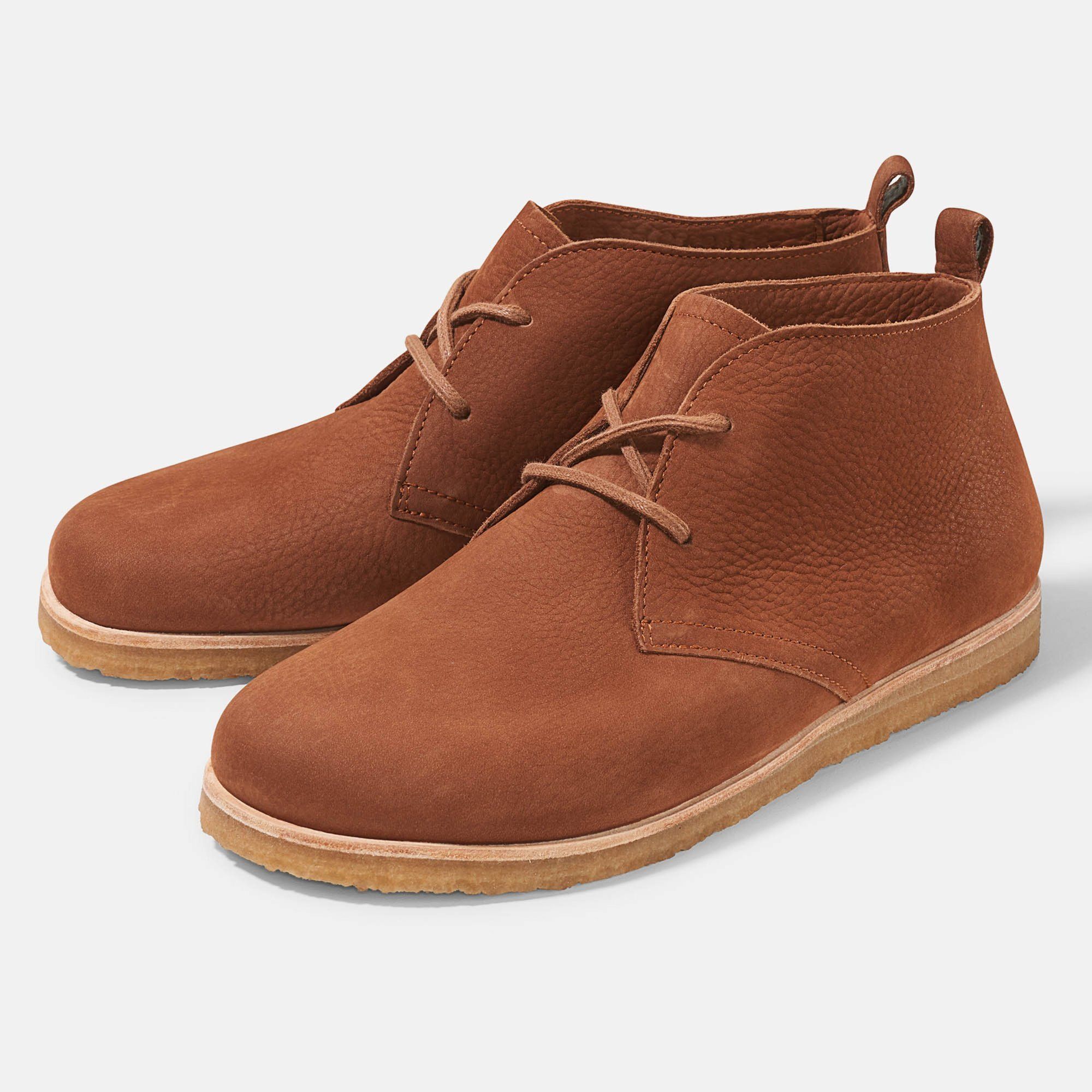 Braune Stiefeletten mit Schnürsenkeln. Hellbraune Sohle. Auf hellem Hintergrund.