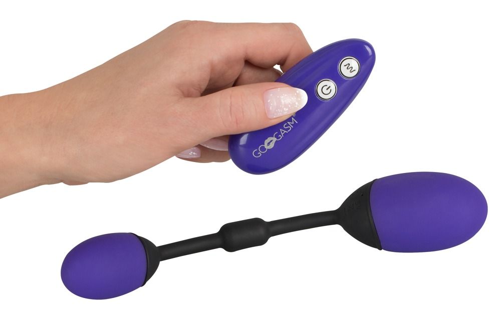 Hand hält Fernbedienung und Produkt mit zwei lila Eiern und schwarzem Stiel. GoGasm-Logo.