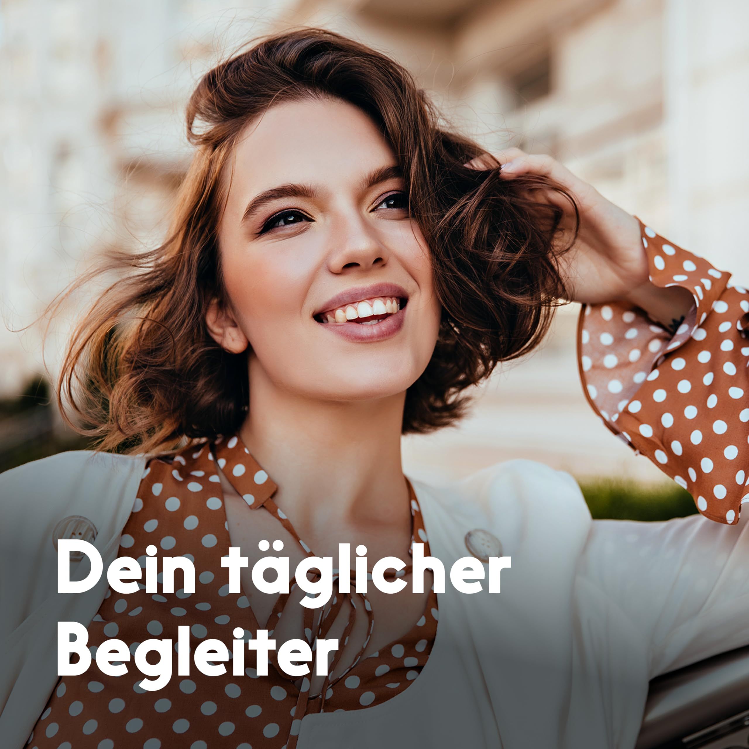 Eine lächelnde Frau mit braunen Haaren. Sie trägt ein weißes Oberteil und eine Jacke mit gepunkteten Ärmeln. Text: Dein täglicher Begleiter.