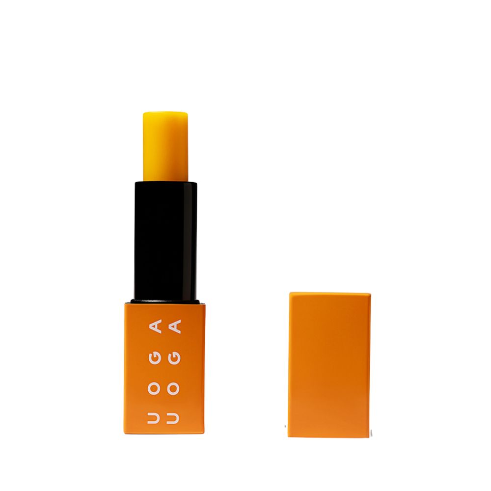 Lippenbalsam mit geöffneter Kappe. Orangefarbener Behälter mit schwarzem Mittelteil und gelbem Balsam. Auf dem Behälter steht "UOGA".