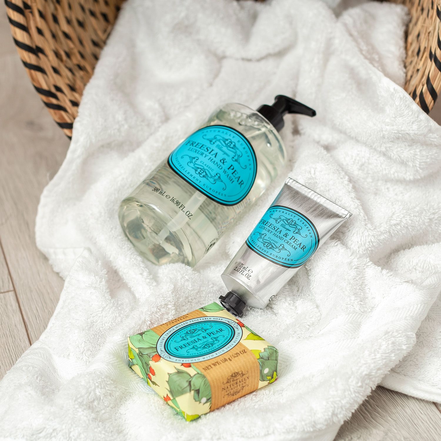 Freesia & Pear Flüssigseife, Handcreme und Seife auf weißem Handtuch.