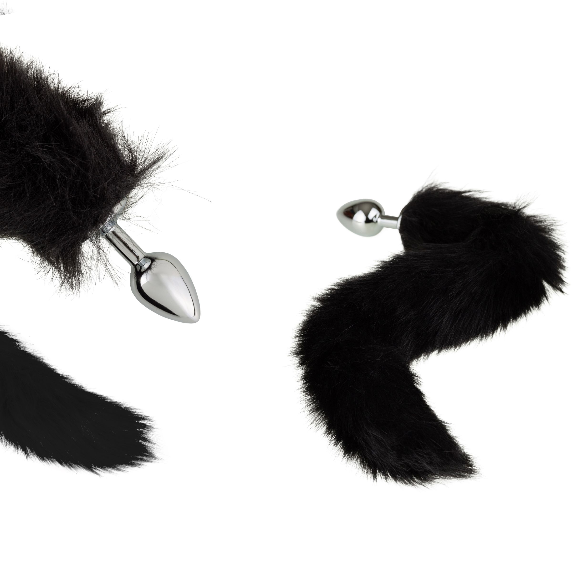 Zwei schwarze Analplugs mit Fellschwanz. Die Plugs haben eine glänzende, metallische Oberfläche.