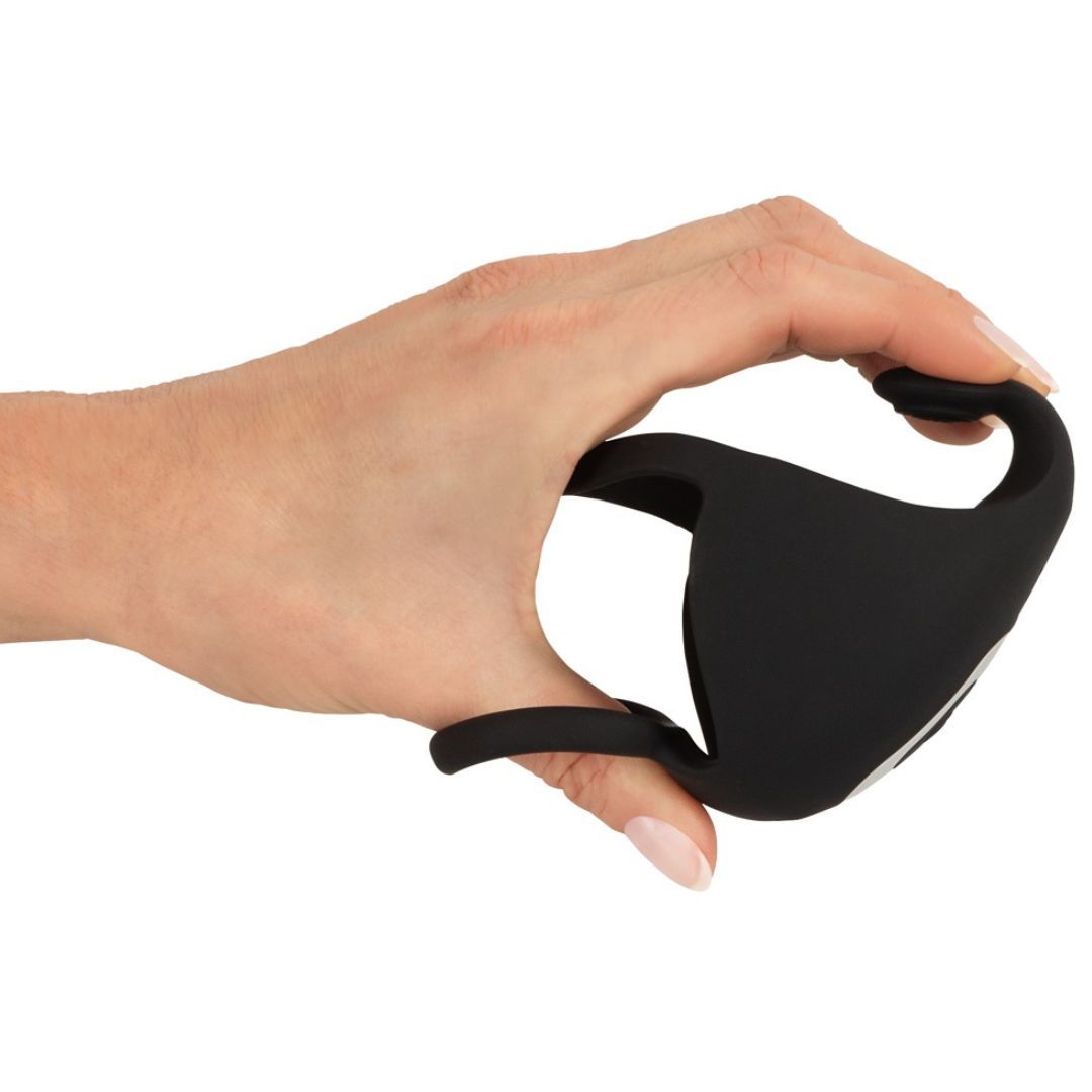 Schwarzer Penis- und Hodenring in Hand gehalten. Flexibles Material. Zwei Ringe und Vibrator-Einheit.
