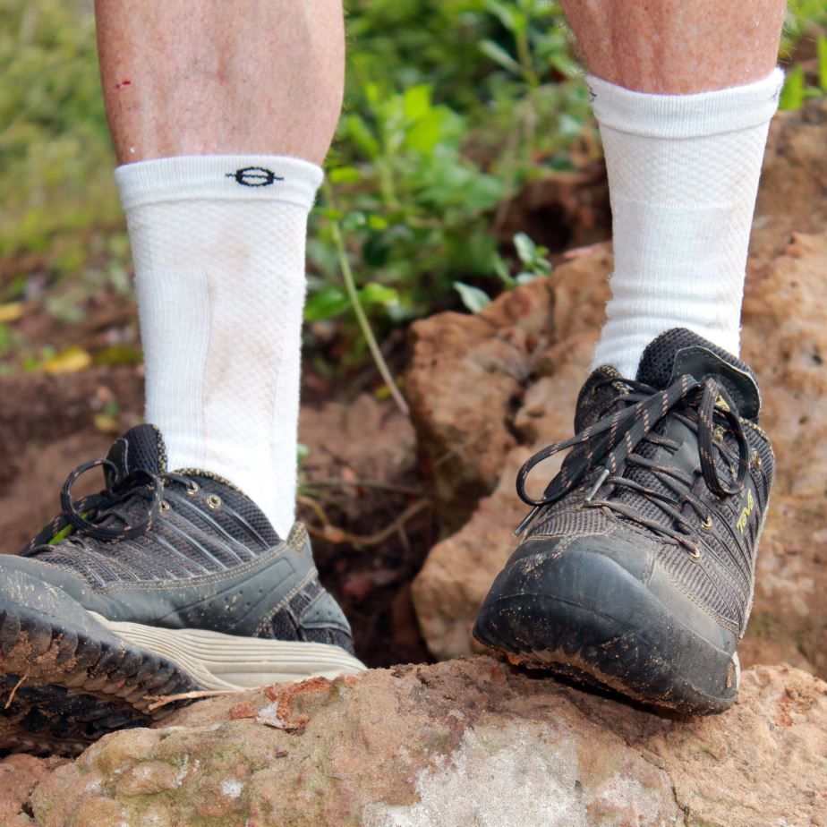 Person trägt weiße Kompressionssocken und schwarze Schuhe. Auf Felsen stehend.