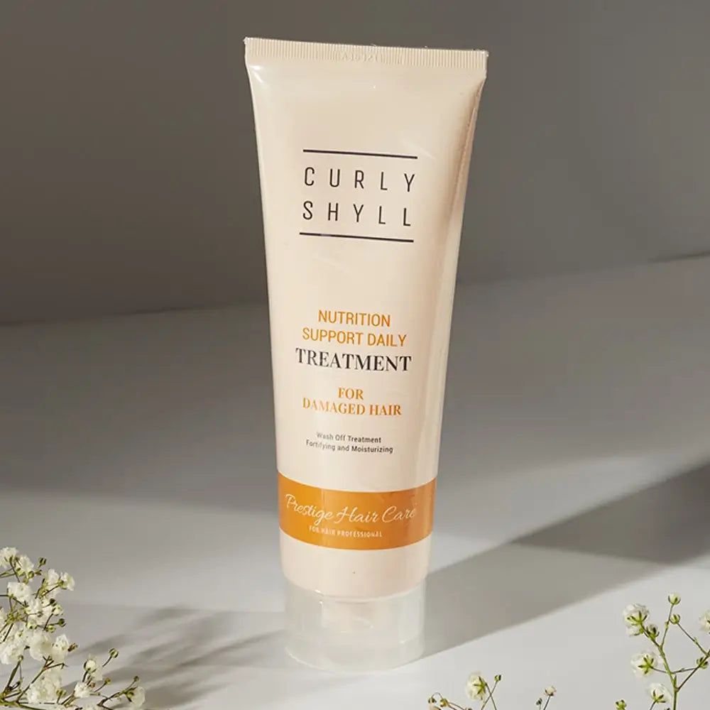 Beige Tube mit Produktnamen und Text. Auf weißem Untergrund. Blumen im Hintergrund.