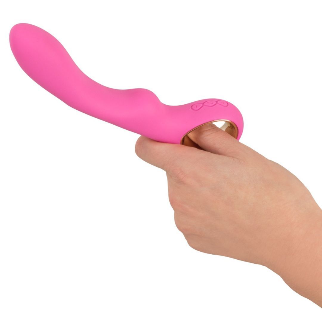 Pinkfarbener Vibrator in einer Hand gehalten. Der goldfarbene Ring umschließt einen Finger.