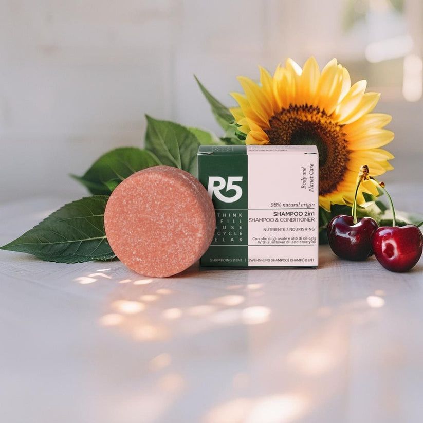 Runde, feste Shampoo-Stücke und Verpackung. Auf Holzoberfläche mit Sonnenblume und Kirschen. Verpackung mit Text.