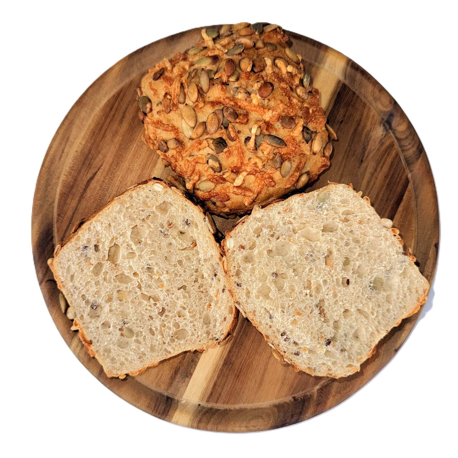 Ein Kürbis-Käse-Brötchen aufgeschnitten auf einem Holzbrett.