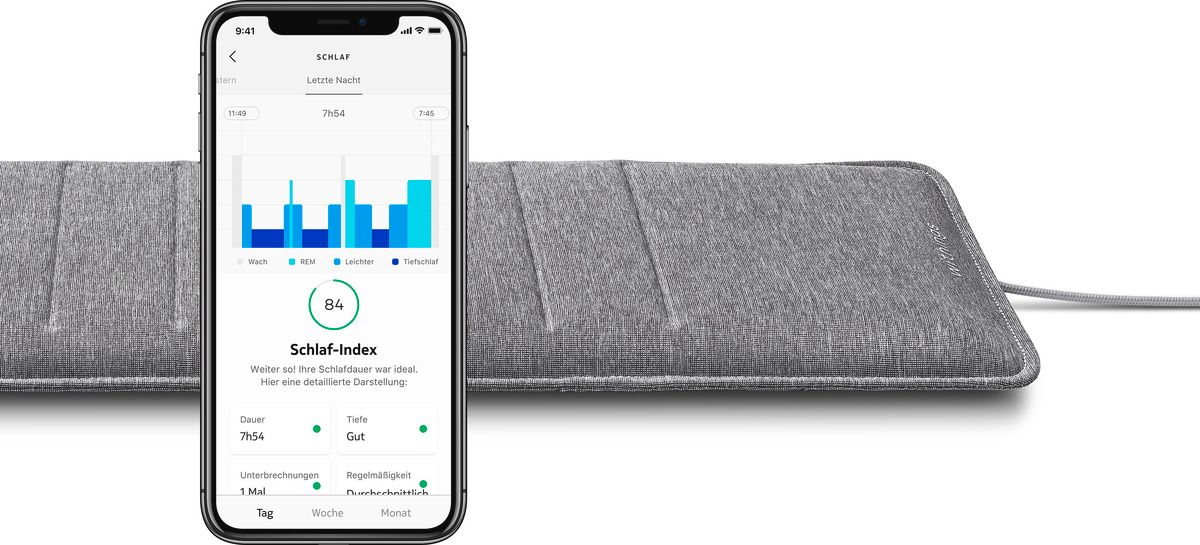 Materasso grigio con smartphone. Dati del sonno visualizzati. Sfondo bianco.