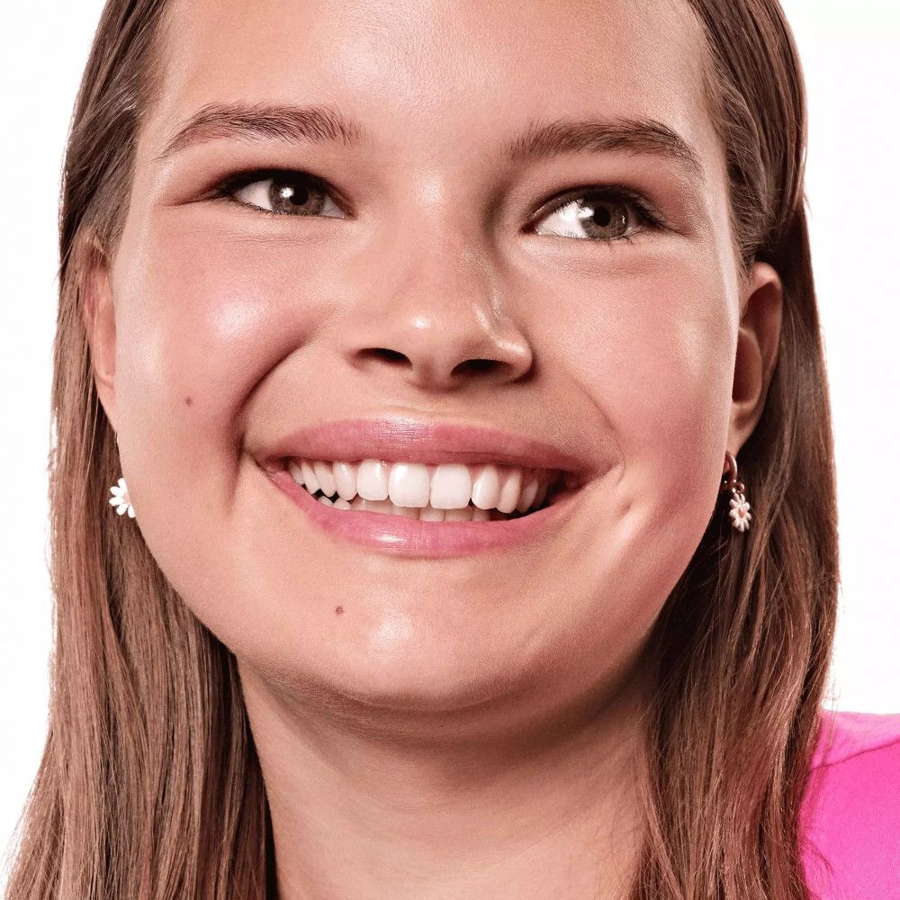 Porträt einer lächelnden Frau. Sie trägt ein pinkes Oberteil und Ohrringe.