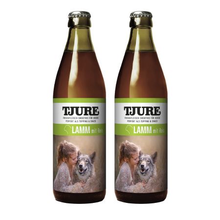 Zwei Flaschen Tjure Hund Lamm Doppelpack. Etikett mit Text und Bild eines Mädchens und eines Hundes. Braune Flüssigkeit.