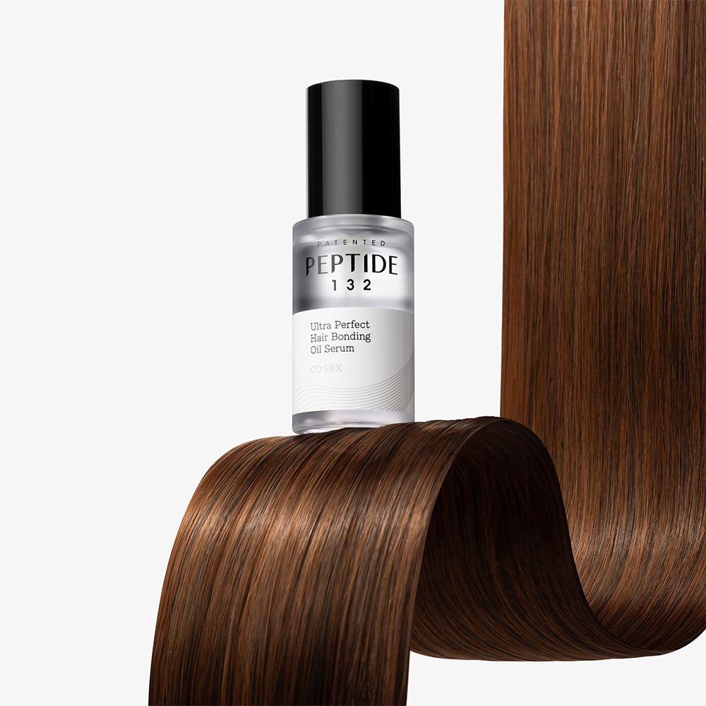 COSRX Peptide 132 Ultra Perfect Hair Bonding Oil Serum in Glasflasche auf gewelltem Haar.