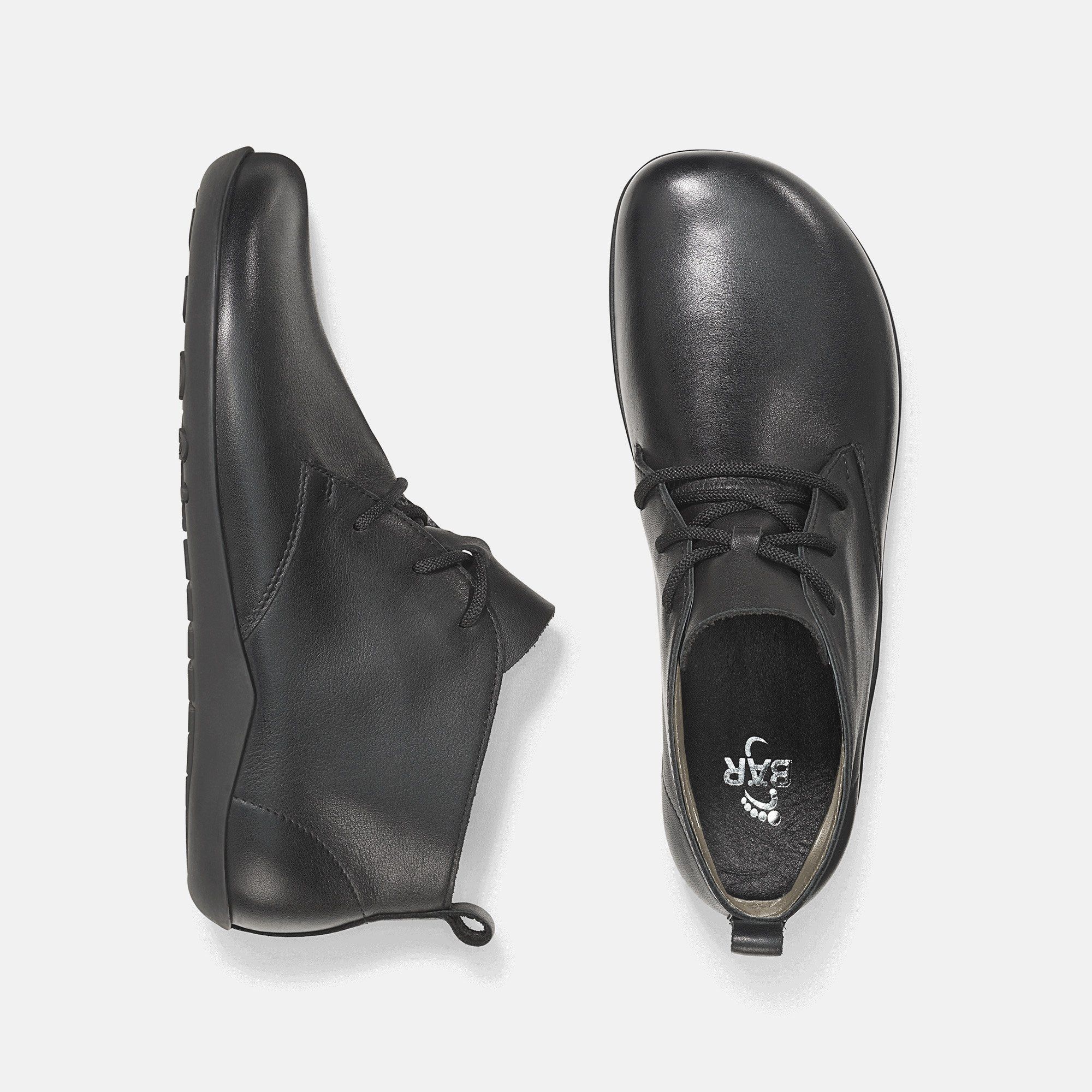 Schwarze Stiefeletten, Draufsicht. Ein Schuh von oben, einer von der Seite. Flache Sohlen.