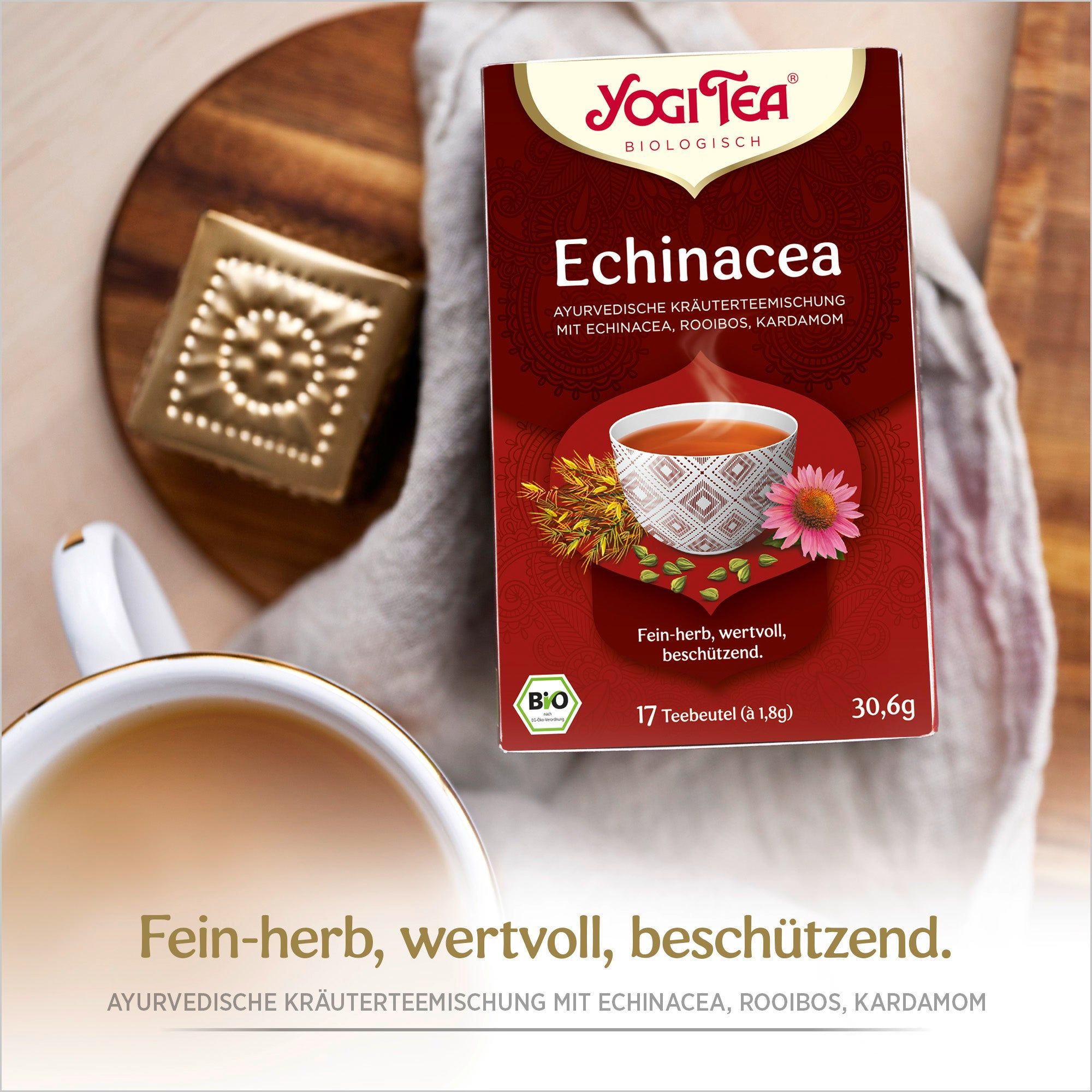 Rote Teepackung mit Logo und Produktbezeichnung. Bio-Siegel. Daneben Tasse Tee und Dekoration.