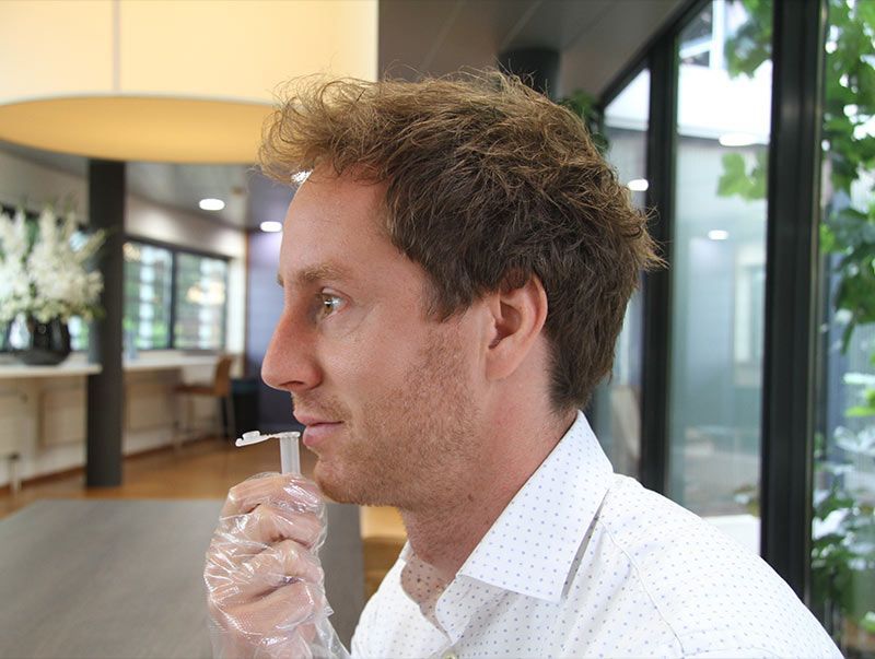 Mann hält einen Speicheltest-Applikator. Der Applikator ist in einer Schutzhülle.