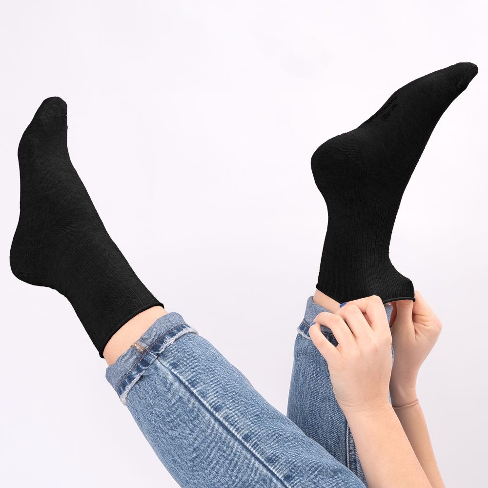 Schwarze Socken ohne Gummibund, eine Person zieht eine Socke an.