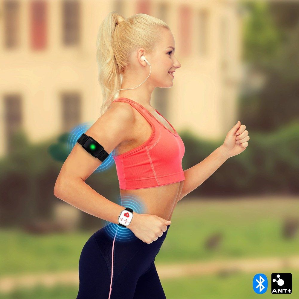 Frau beim Laufen mit Armpulsgurt und Smartwatch, die Herzfrequenzdaten über Bluetooth überträgt.