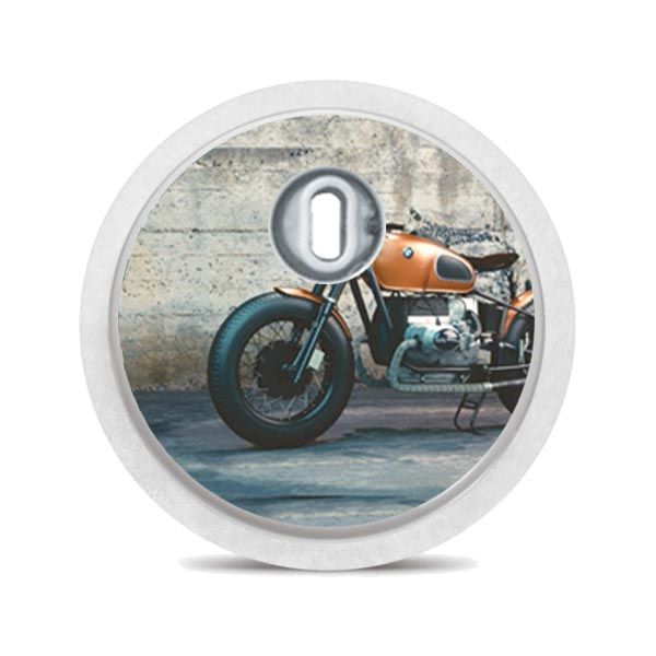 Runder Aufkleber mit Motorradmotiv. Motorrad vor Betonwand. Weißer Rand, silberner Mittelteil.