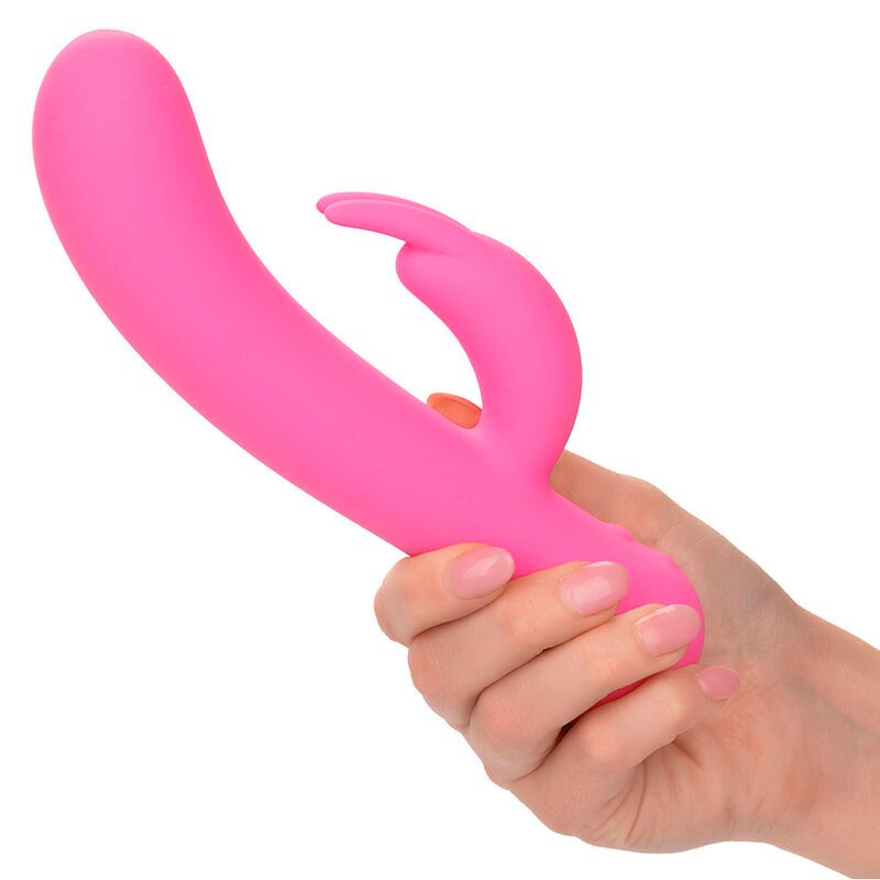 Rosa Dualstimulator in einer Hand gehalten. Gebogene Form mit Hasenohren-Aufsatz. Aus Silikon.