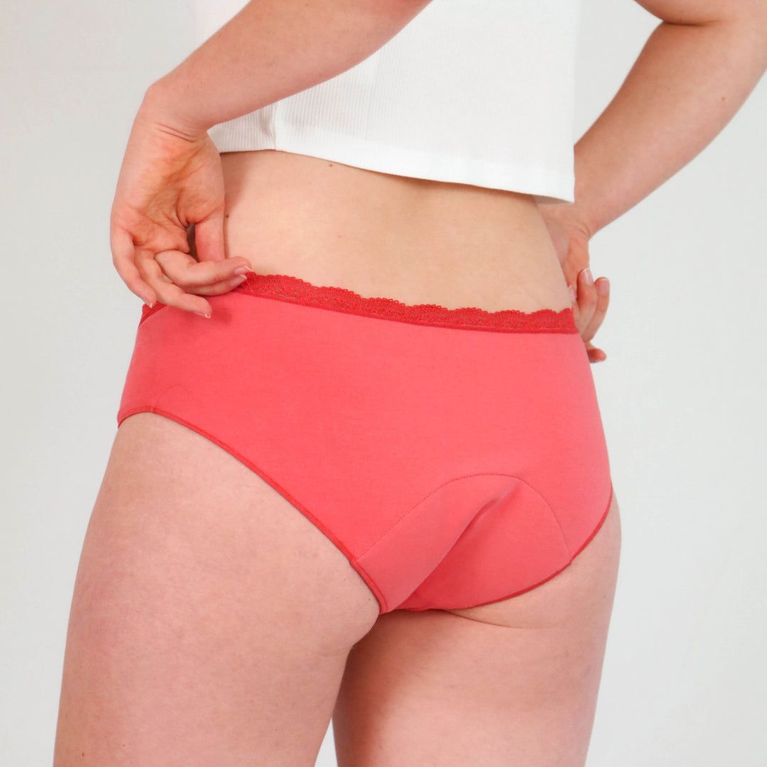 Rote Periodenunterhose, Hipster-Schnitt, von hinten gesehen. Spitze am Bund. Person hält die Hose fest.