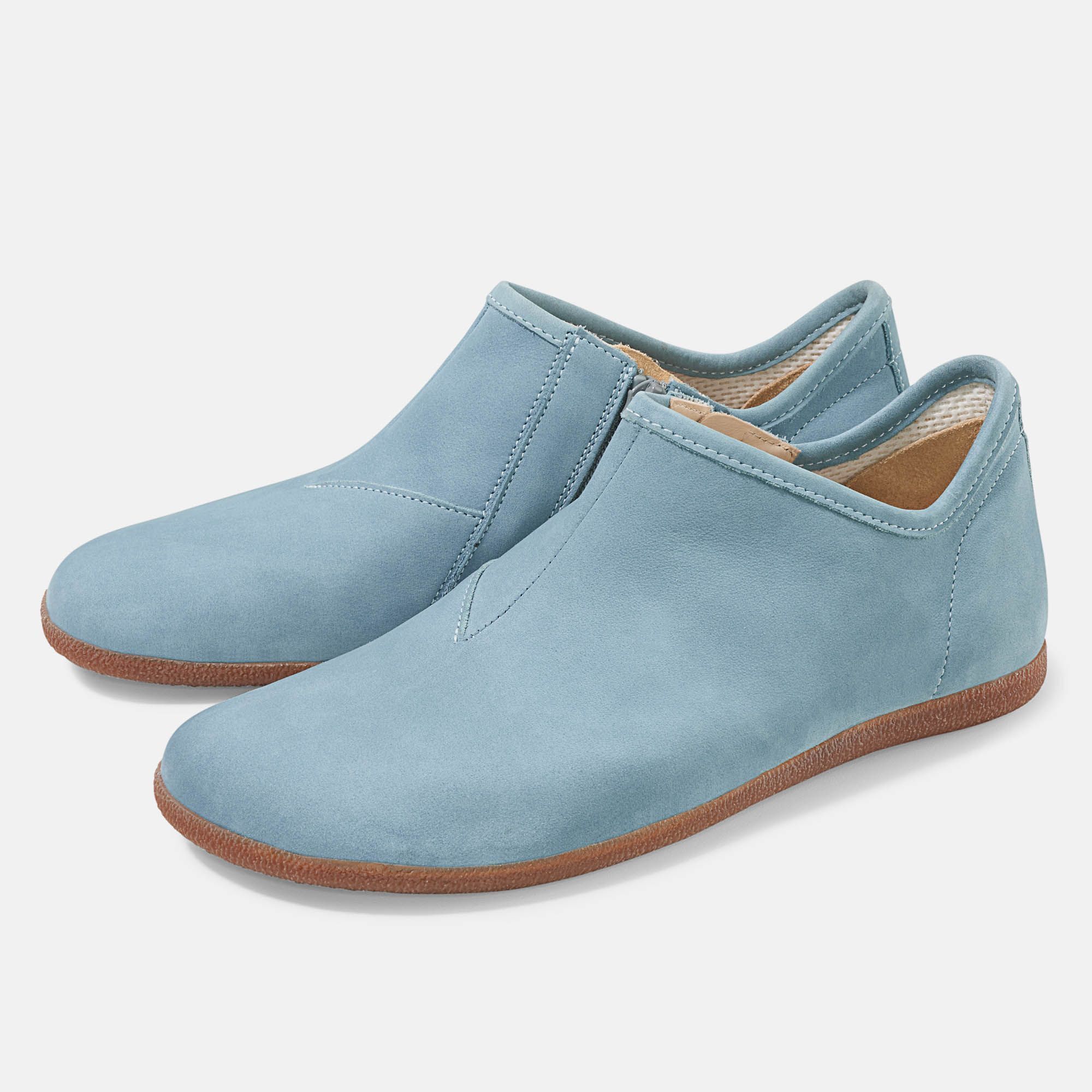 Hellblaue Slipper mit brauner Sohle. Seitlicher Reißverschluss. Weite Form. Zwei Schuhe nebeneinander.
