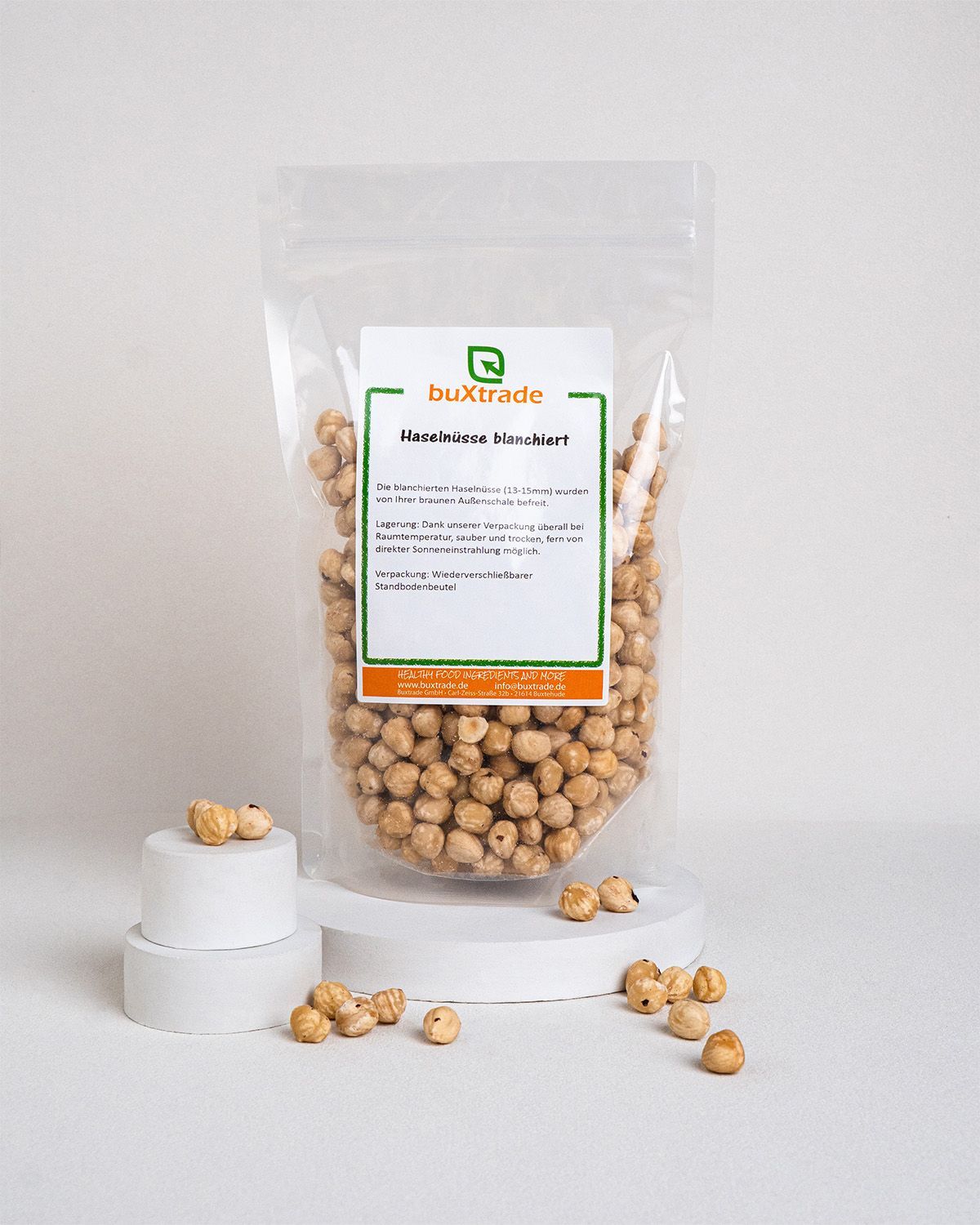 Verpackung mit blanchierten Haselnüssen auf weißen Podesten. Produktetikett sichtbar.
