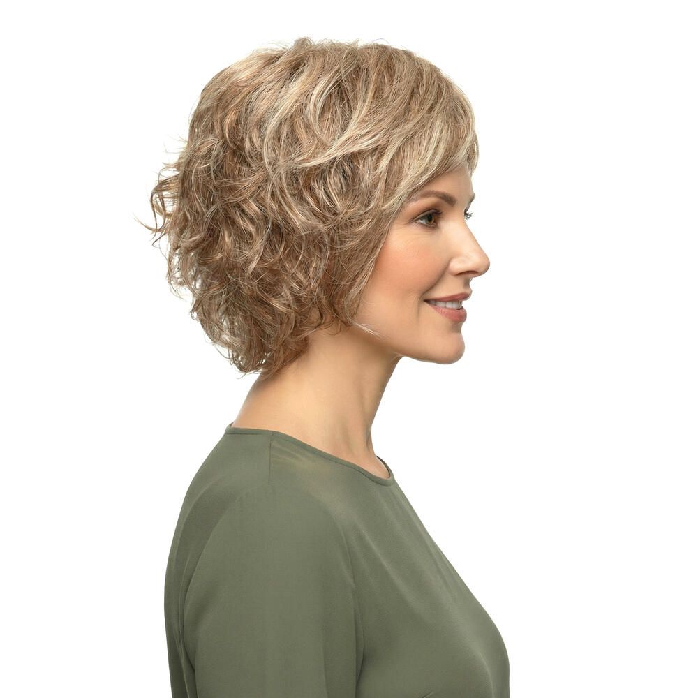 Kurzhaarperücke mit blonden Strähnen. Seitenansicht einer Frau mit Perücke und grünem Oberteil. Blick zur Seite.