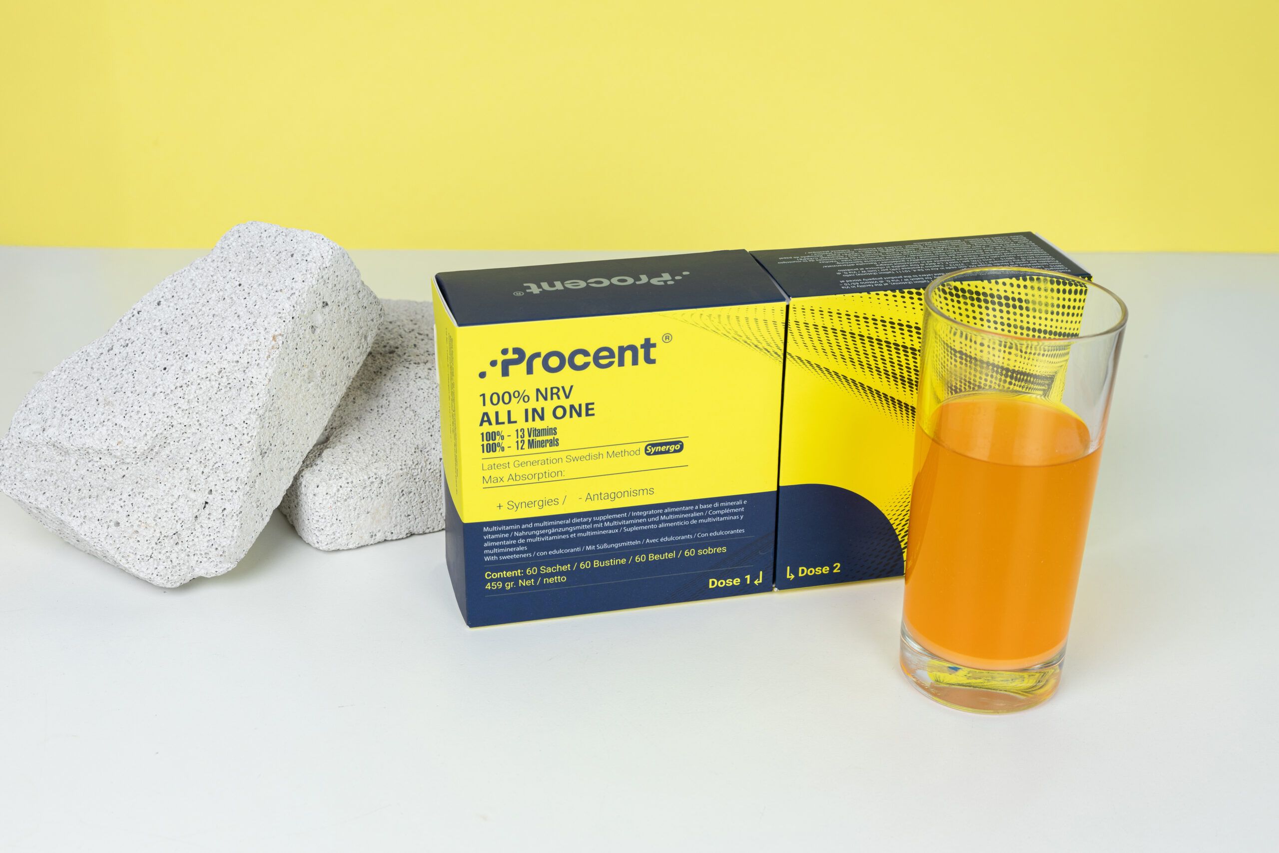 Prozent 100% NRV All in One Nahrungsergänzungsmittel-Box mit Glas Orangensaft und zwei Steinen.