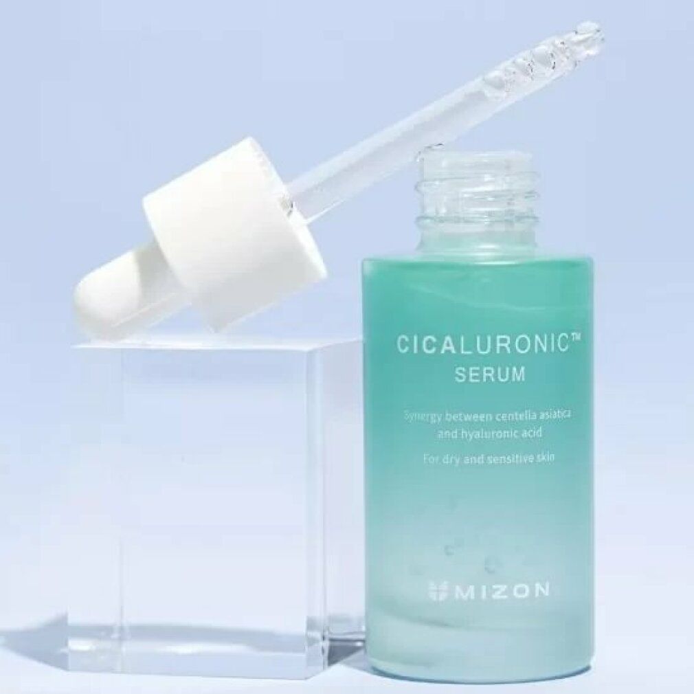 Grüne Serumflasche mit Pipette auf einem transparenten Block. Aufschrift: Cicaluronic Serum. Marke: Mizon.