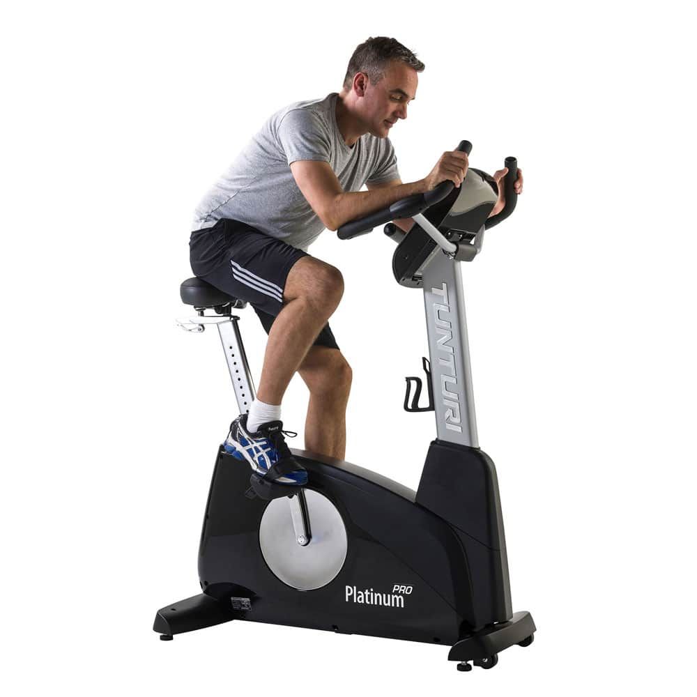 Mann auf Ergometer. Schwarz, silberfarben. Tunturi-Logo. Platinum-Schriftzug. Sattel, Lenker, Pedale.