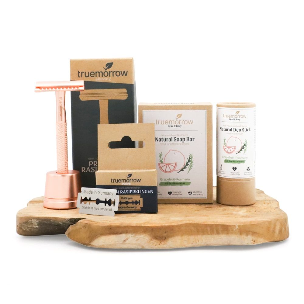 Geschenkset mit Rasierer, Rasierklingen, Seife und Deostift. Produkte von truemorrow auf Holzbrett. Rasierer roséfarben.