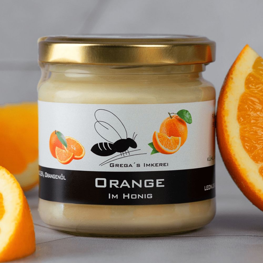 Glas Honig mit Orangengeschmack, umgeben von Orangenstücken und Bienenmotiv.