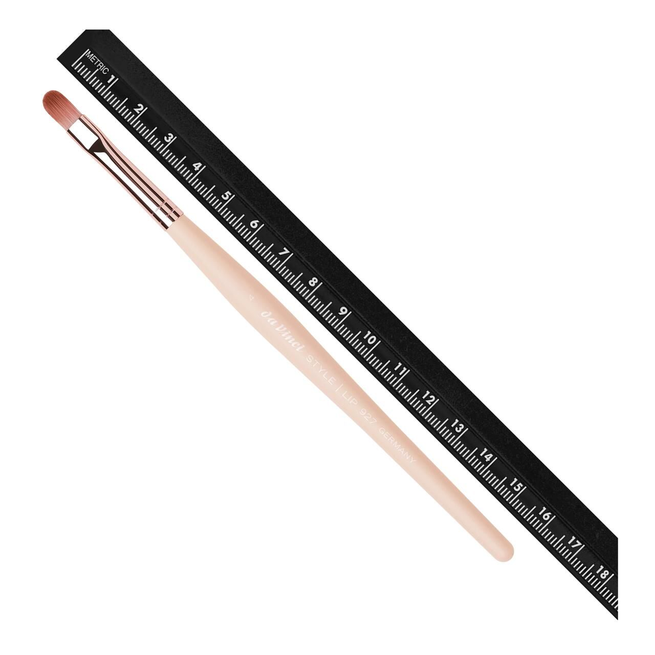 Lippenpinsel neben einem Lineal. Der Pinsel hat einen hellen Holzgriff, Metallzwinge und flachen, ovalen Pinselkopf. Auf dem Griff steht "Da Vinci".