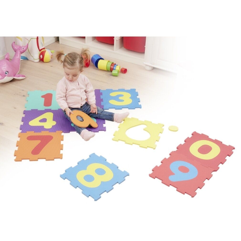 Kind sitzt auf Puzzlematten mit Zahlen. Einzelne Puzzleteile mit Zahlen 0-9. Kind hält Zahl 9.