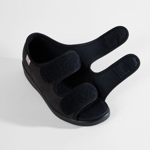 Schwarze Sandale mit Klettverschluss, offenem Zehenbereich und einem kleinen roten Logo auf der Seite.
