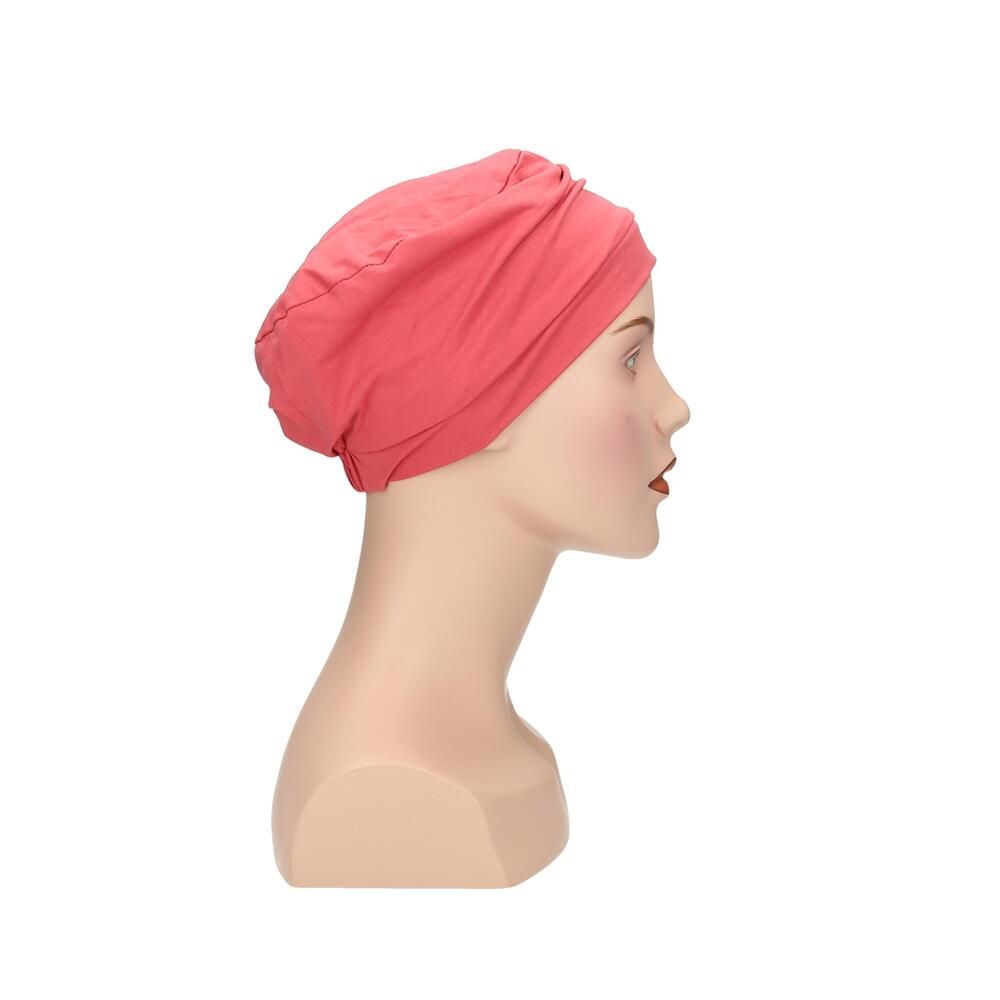 Korallenfarbener Turban auf Büste. Stoffhaube mit Faltenwurf. Seitenansicht.