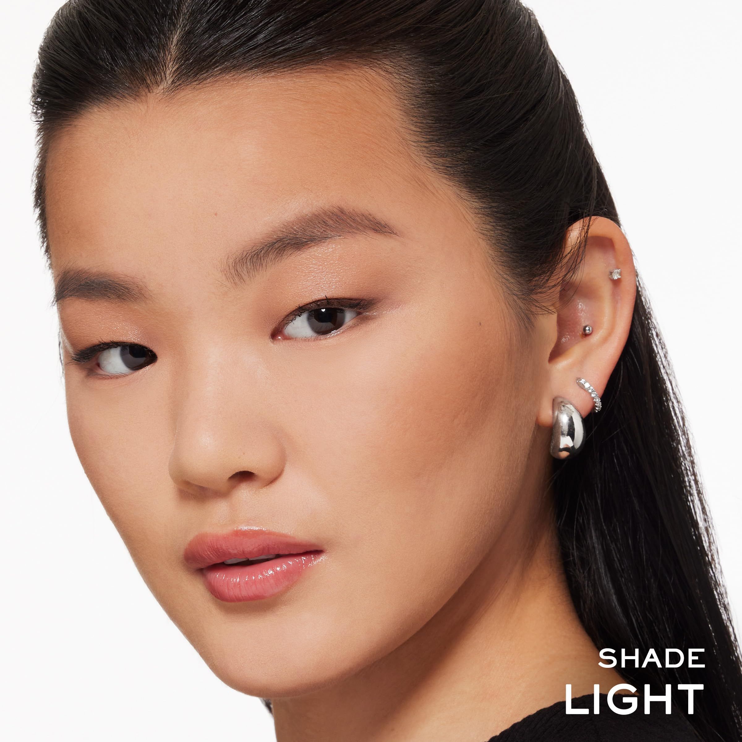 Nahaufnahme einer Frau mit hellem Teint. Aufschrift: SHADE LIGHT. Sie trägt Ohrringe.