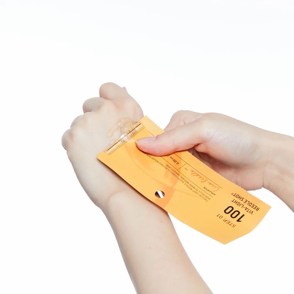 Ein einzelnes Ampullen-Applikator mit Serum auf einer Hand, gehalten von einer zweiten Hand.