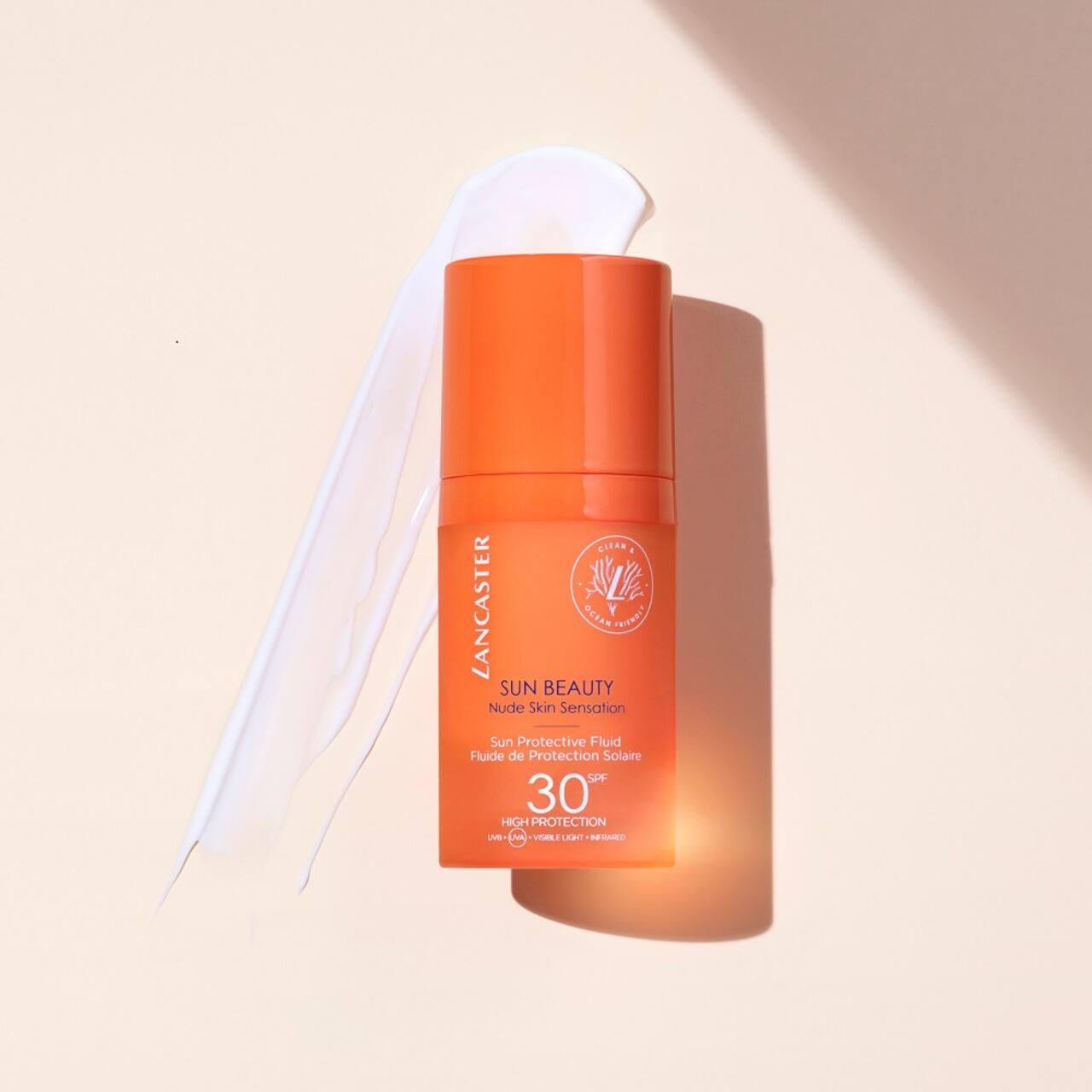 Orangefarbene Flasche mit weißem Produkt daneben. Aufschrift: Lancaster SUN BEAUTY, Nude Skin Sensation, SPF 30.