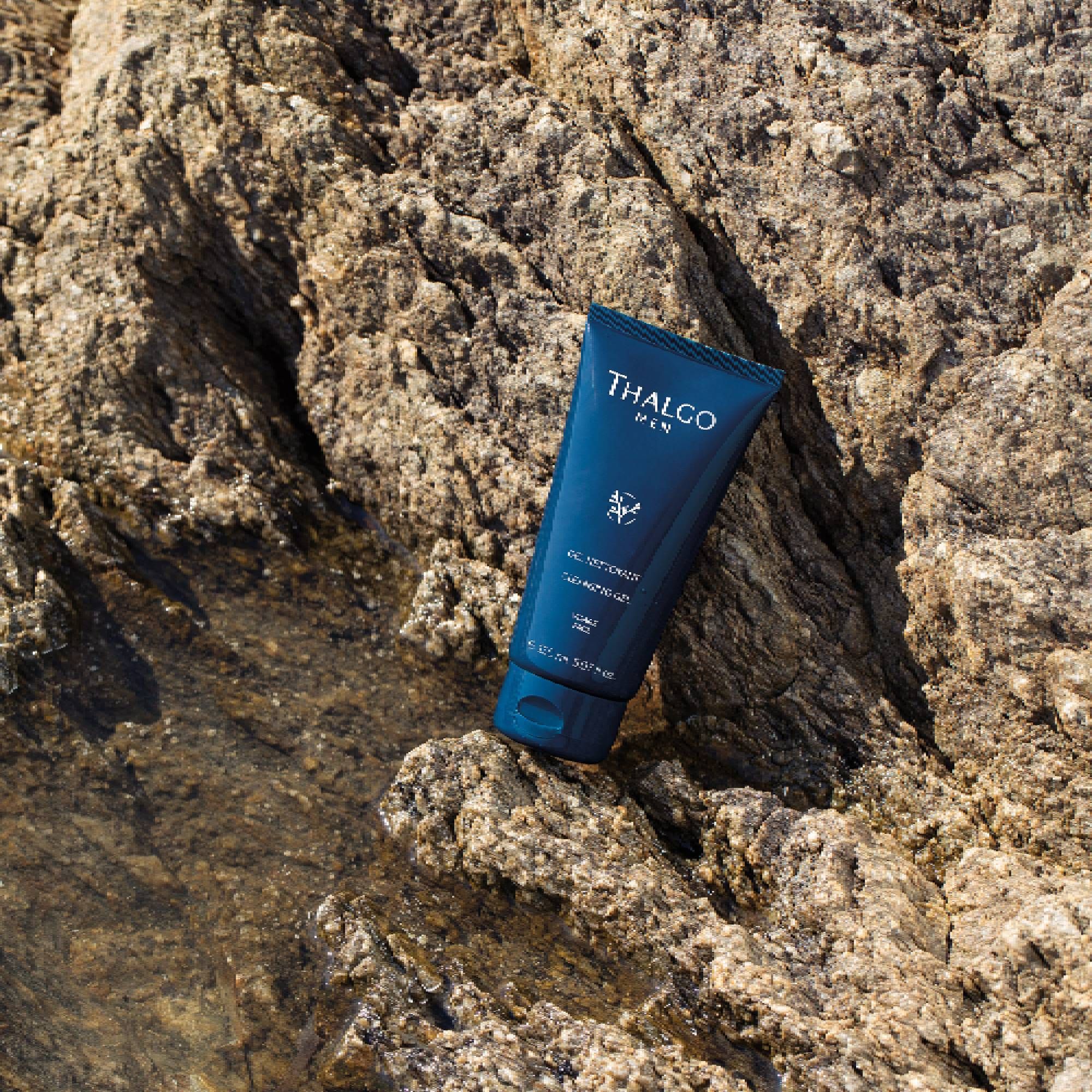 Dunkelblaue Tube auf Felsen. THALGO MEN, Reinigungs-Gel. Blaue Kappe.