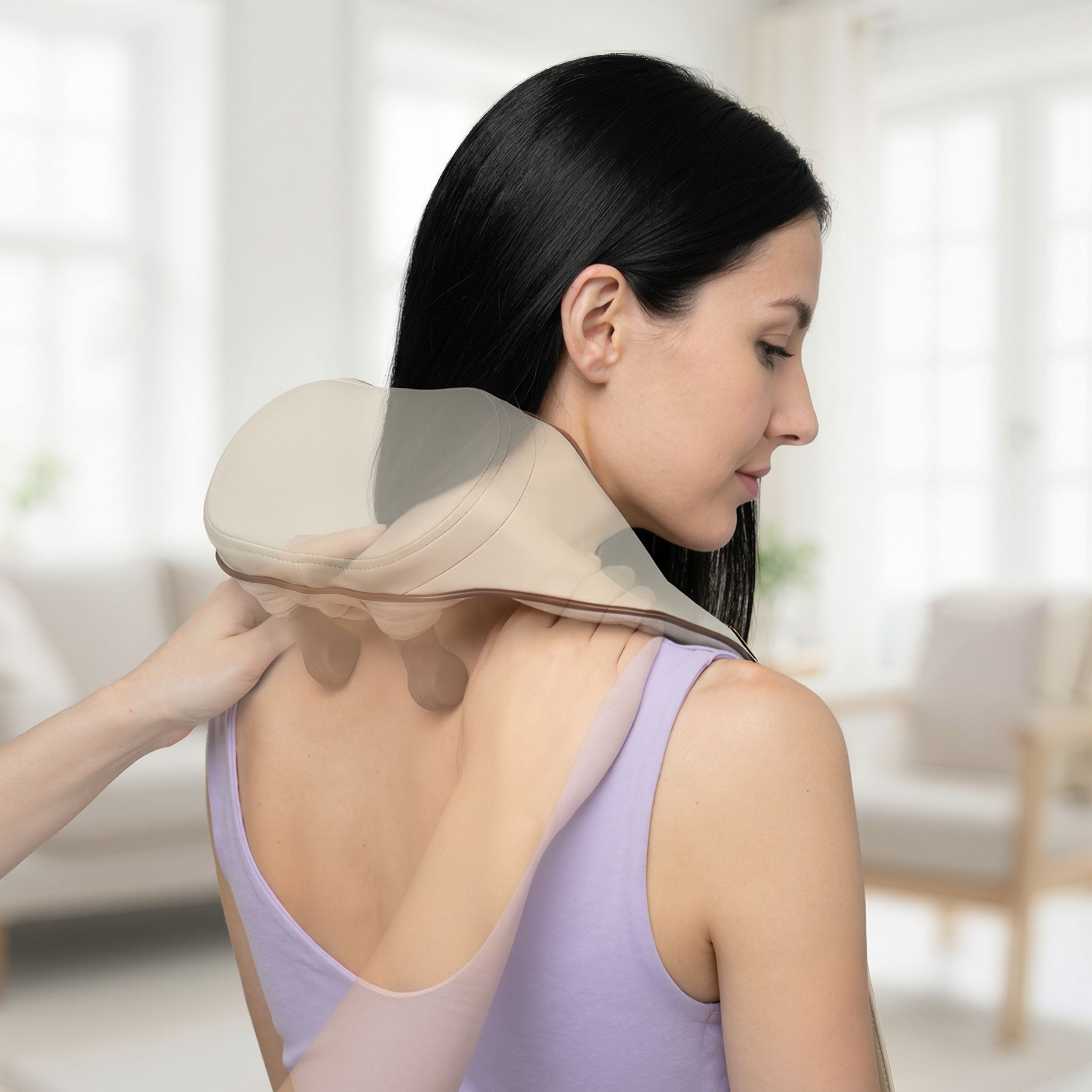 Nacken- und Schultermassagegerät, cremefarben mit braunen Akzenten, an einer Frau. Hände massieren den Nacken. Hintergrund: Wohnzimmer.