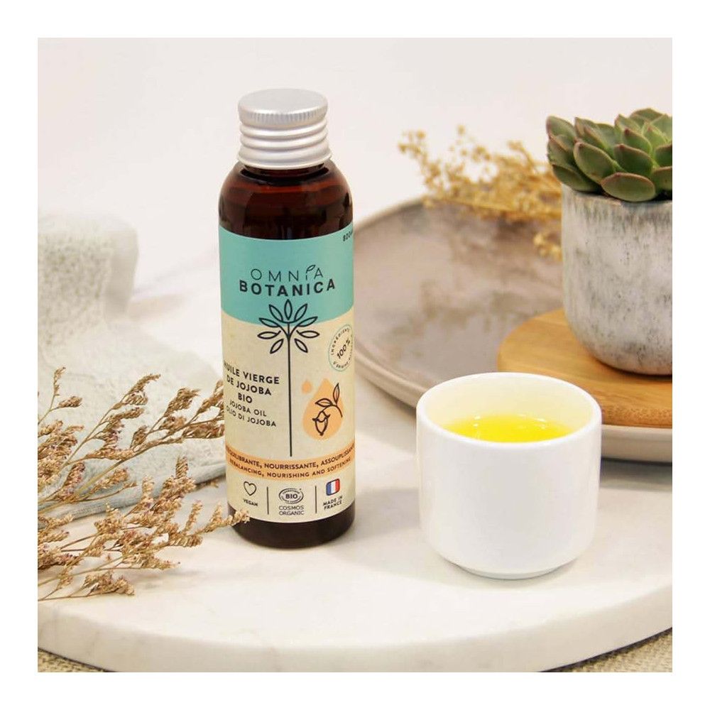 Braune Glasflasche mit silbernem Deckel. Etikett mit Produktnamen. Neben einem Becher mit Flüssigkeit.