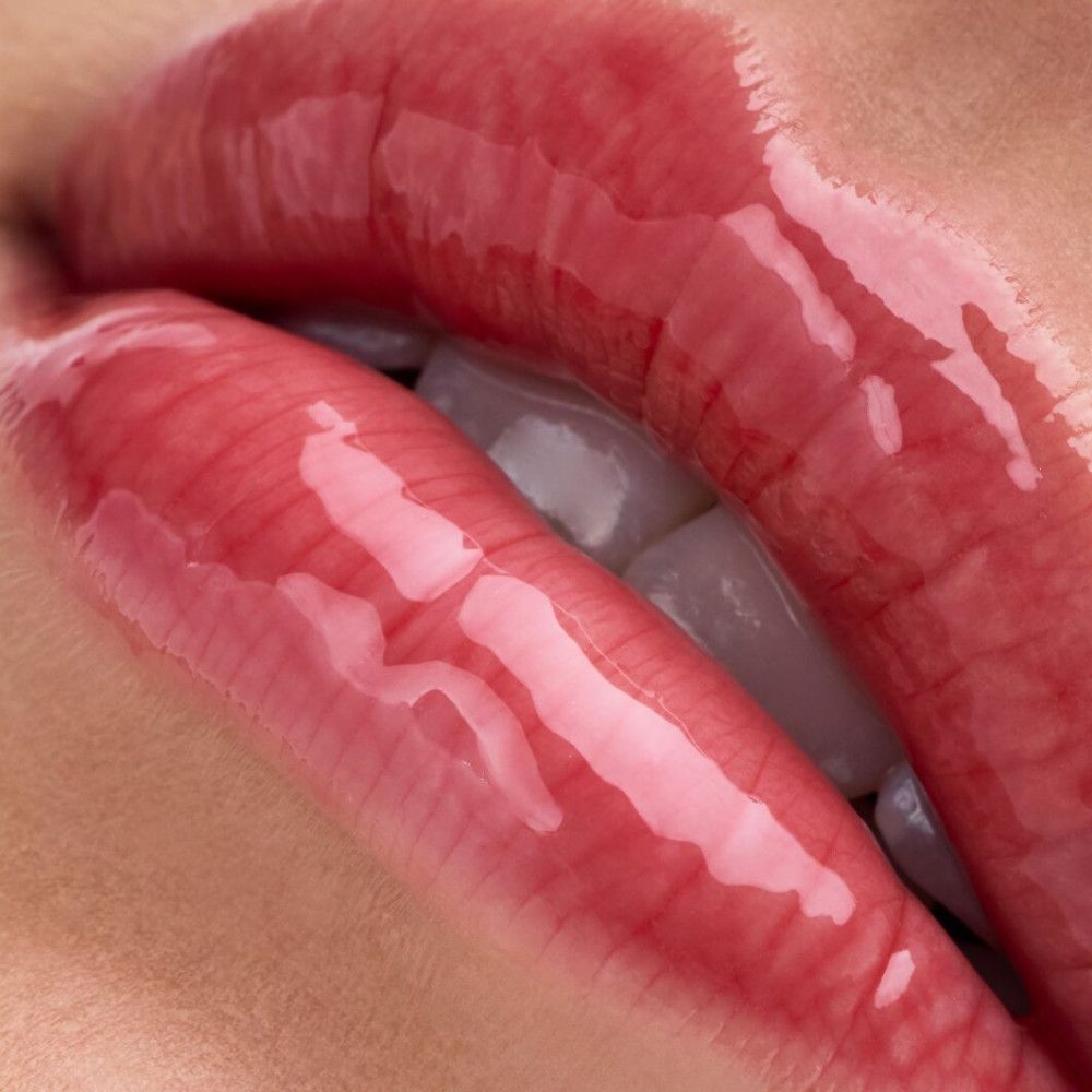 Nahaufnahme von Lippen mit glänzendem Lip Balm. Lippen sind rot und glänzend.