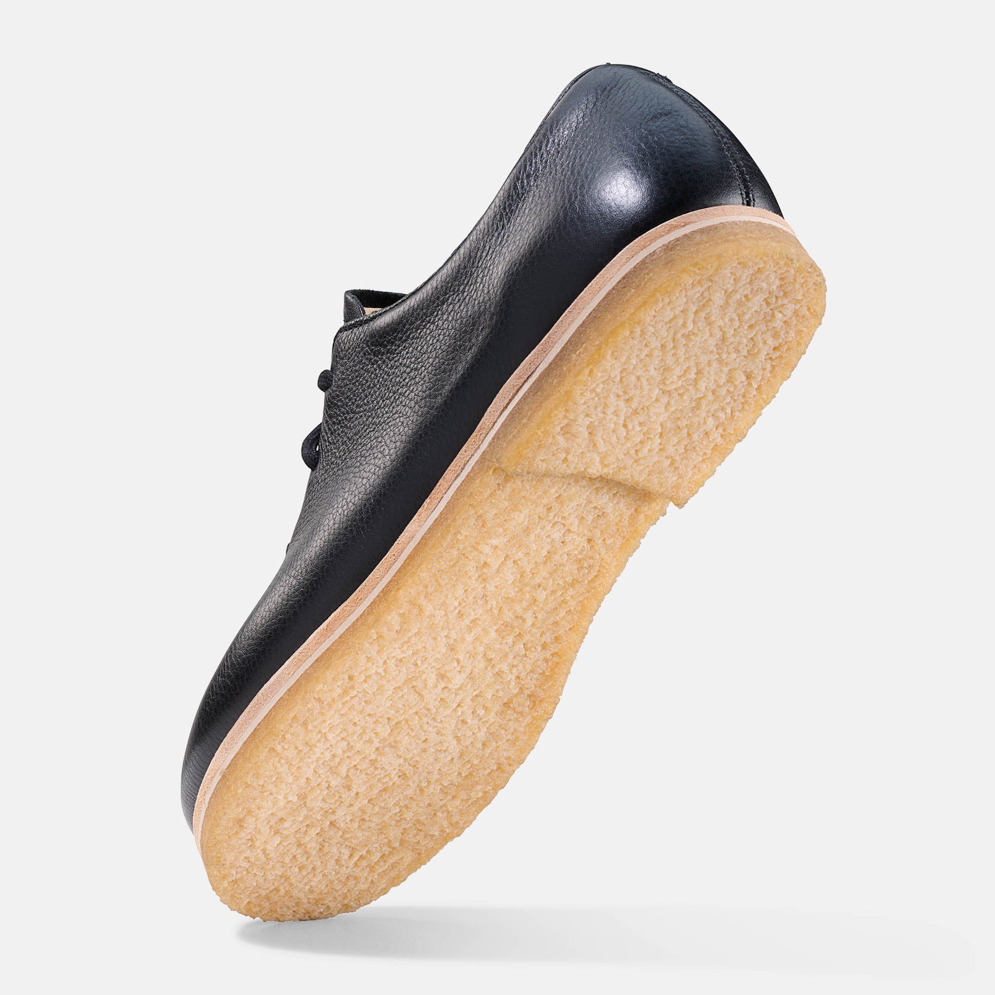 Schwarzer Lederschnürschuh. Helle Sohle. Schuh von unten schräg.