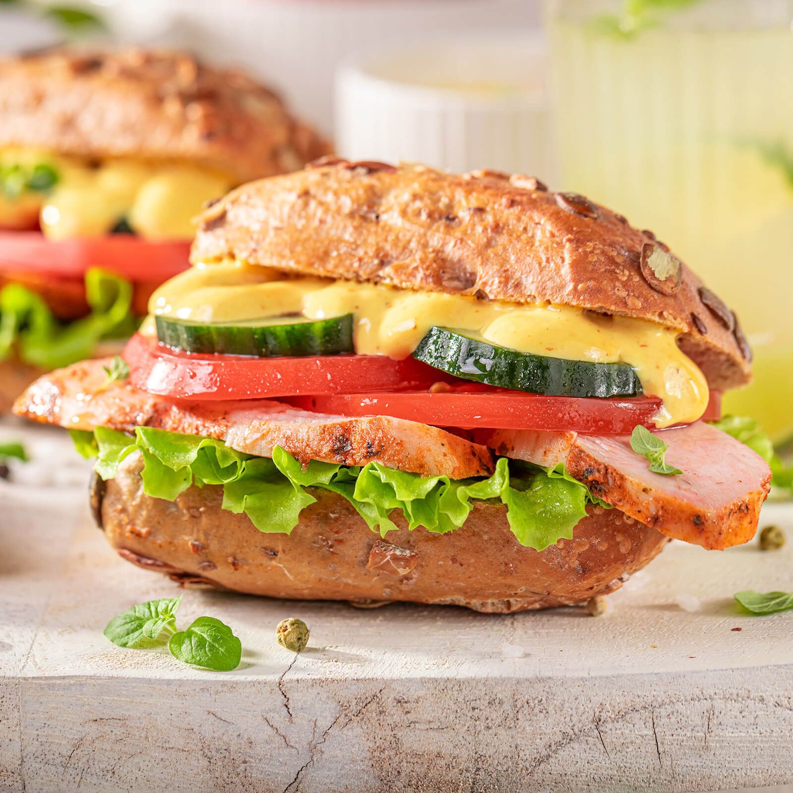 Sandwich mit Kürbis-Käse-Brötchen, Fleisch, Salat, Tomate, Gurke und Sauce.